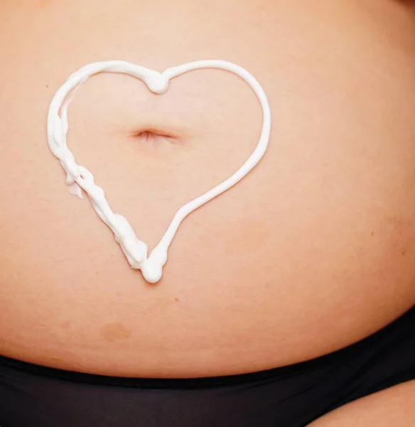Красивый снимок живота беременной женщины с белым сердцем — стоковое фото