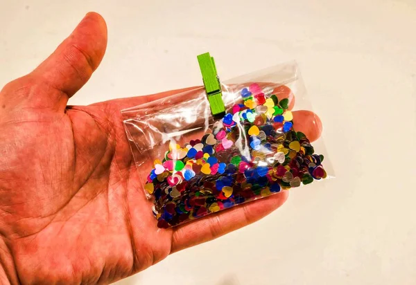 Person que contiene un pequeño paquete de partículas cardíacas coloridas. — Foto de Stock