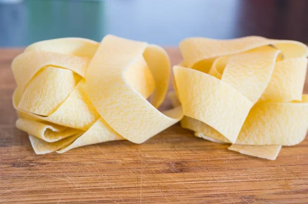 Närbild skott av två rå tagliatelle pasta på ett träbord — Stockfoto