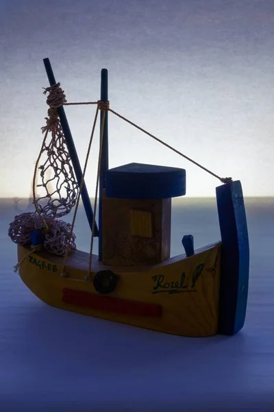 Vertikal bild av ett träfartyg leksak placeras på en blå yta med en ljus bakgrund — Stockfoto