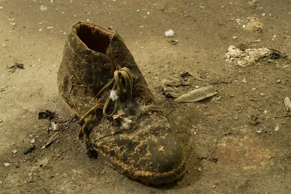 旧的破烂不堪的脏鞋子在地上拍的特写照片 — 图库照片
