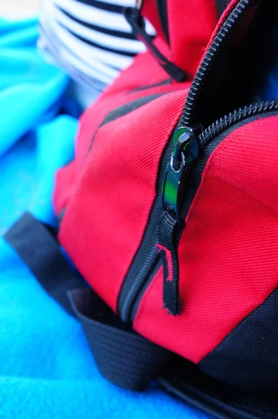 Nahaufnahme eines schwarz-roten Reißverschlusses an einem Rucksack im Sonnenlicht mit verschwommenem Hintergrund — Stockfoto