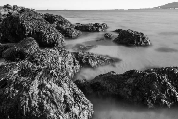 Czarno-białe ujęcie skał i bardzo zamazane morze z plaży Sandsfoot w Dorset, UK — Zdjęcie stockowe