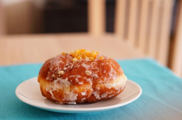 Primo piano di un Malasada sul piatto su un tavolo di legno sotto le luci con uno sfondo sfocato — Foto Stock