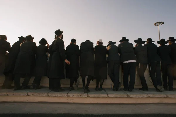 Ludzie w czarnych kostiumach i kapeluszach stojący na granicy mostu — Zdjęcie stockowe