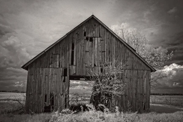 一张灰色的照片 拍的是一个废弃的木制谷仓 后面是一片漆黑的天空 — 图库照片