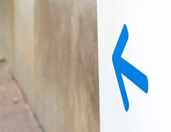 Bílá značka s modrým ukazatelem udávající směr na ulici — Stock fotografie