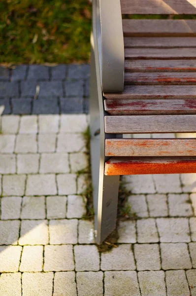 Eine Vertikale Hochwinkel Nahaufnahme Einer Holzbank Mit Kopfsteinpflaster Unten — Stockfoto