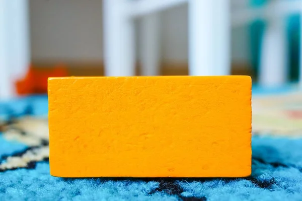 Pomarańczowa prostokątna zabawka dla dzieci umieszczona na wielobarwnej powierzchni — Zdjęcie stockowe
