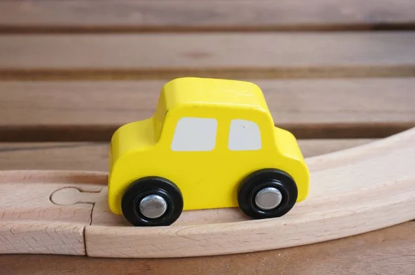 Encerramento tiro de carro de brinquedo de madeira amarela em uma pista de madeira — Fotografia de Stock