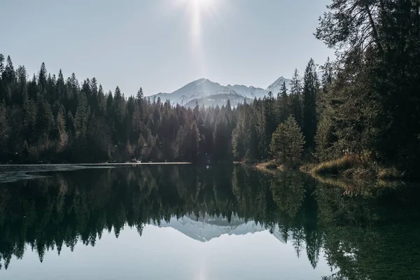 Lago cercado por montanhas e florestas com árvores refletindo sobre a água — Fotografia de Stock