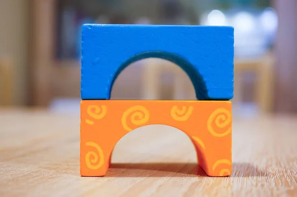 Closeup of small colorful toy figures on a wooden table under the lights with a blurry background