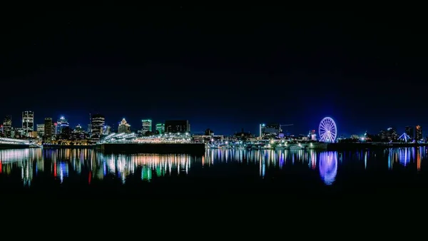 Escala nocturna en el parque Dieppe, con una rueda de Ferris iluminada y reflejos claros sobre el río. — Foto de Stock