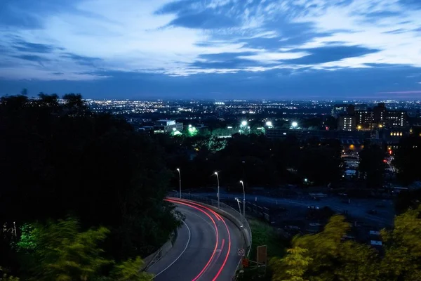 Ночная фотография фонарей на искривленной городской дороге на фоне города — стоковое фото