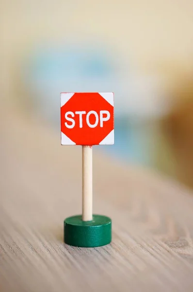 Снимок миниатюрной игрушки с зеленой подставкой на деревянном столе — стоковое фото