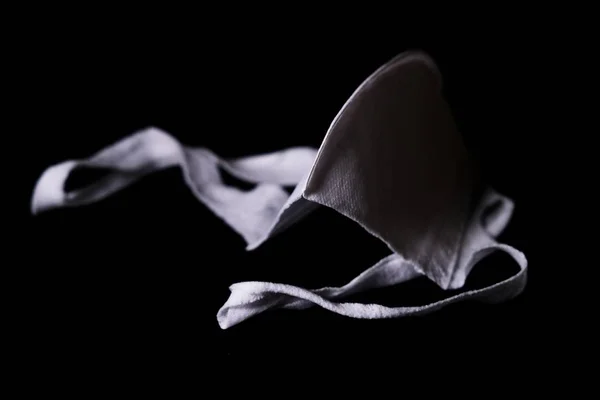 Снимок использованной маски для лица для защиты от коронавируса выделен на черном фоне — стоковое фото
