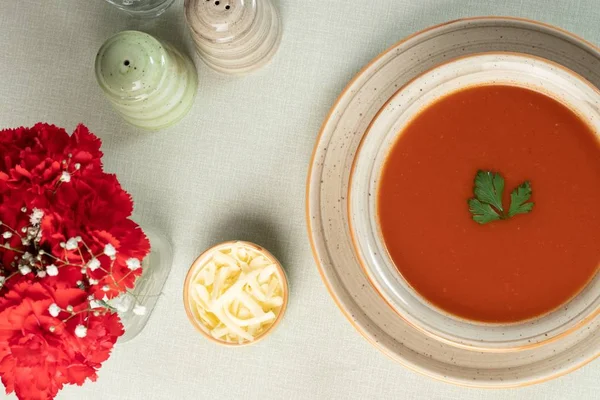 Vue d'ensemble de la soupe aux tomates avec des fleurs et un fromage tranché à côté — Photo