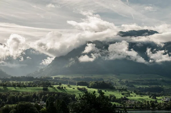 Paisaje de colinas cubiertas de vegetación y niebla bajo la luz del sol y un cielo nublado. — Foto de Stock