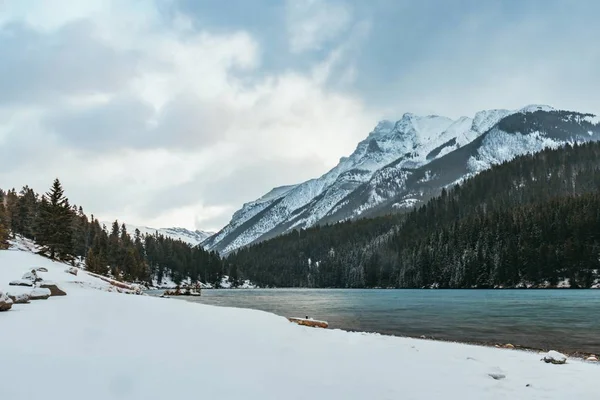 日光の下で雪に覆われた岩の多い山々に囲まれた湖の美しい景色 — ストック写真