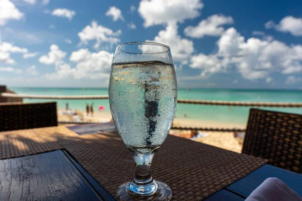 Water in a transparent glass with beach on the background in Aruba Royalty Free Stock Photos