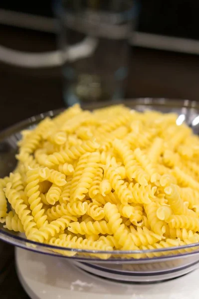 Szekrény nyers Fusilli egy tál alatt a fények homályos háttér — Stock Fotó