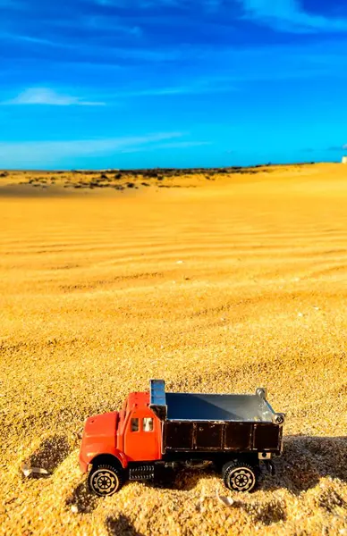 Tiro vertical de um brinquedo de caminhão na areia em um dia ensolarado — Fotografia de Stock