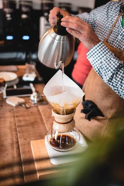 Függőleges lövés egy átlátszó edény szűrésére kávé a fa asztalon — Stock Fotó