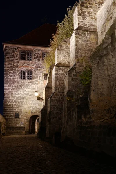 Vertical shot of a cobblestoned path leading to the entrance of a fortress at nighttime — Stock Photo, Image