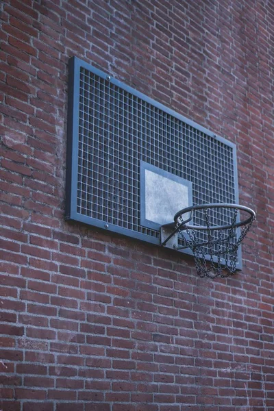 Ampio scatto di un angolo di un anello di basket su un muro di mattoni di un edificio — Foto Stock