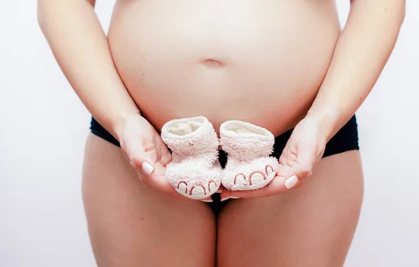 맨 위에 분홍색 아기 구두를 들고 있는 임신 한 여자 — 스톡 사진