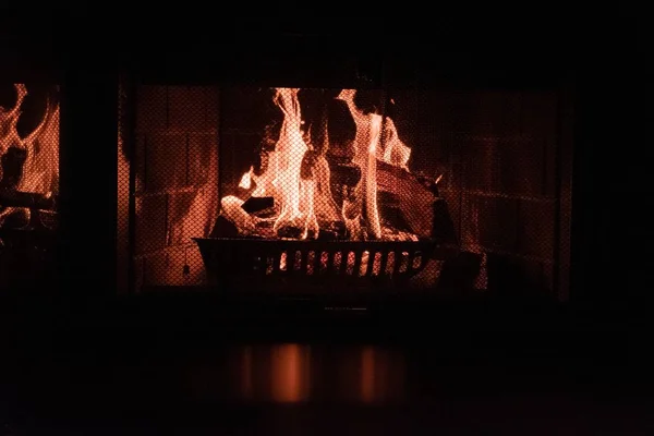 Tuğladan şöminenin içinde ekranı olan bir yangının yakın çekim görüntüsü. — Stok fotoğraf