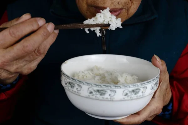 Anziana donna cinese mangiare riso in una ciotola con bacchette — Foto Stock