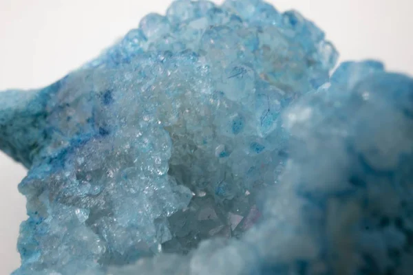 Tiro de close-up extremo de uma pedra de cristal com cor azul contra um fundo branco — Fotografia de Stock