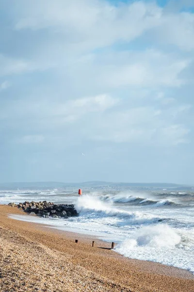 Vertikale Aufnahme von Wellen beim Waschen des Sandstrandes bei bewölktem Wetter — Stockfoto