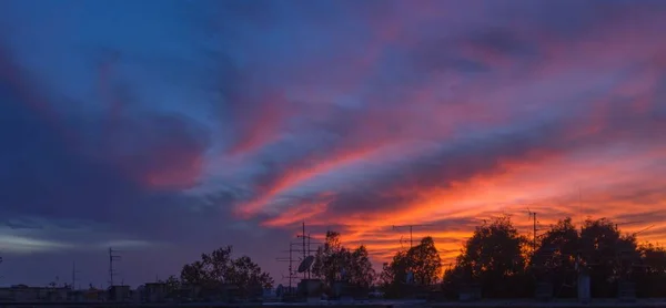 Tiro panorâmico de pôr-do-sol em zíper novo com silhuetas de antena de um edifício velho — Fotografia de Stock