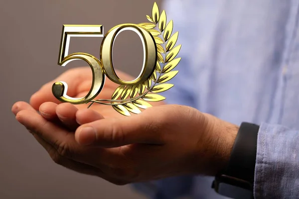 Az 50-es szám egy arany tüske mellett valakinek a kezén. — Stock Fotó