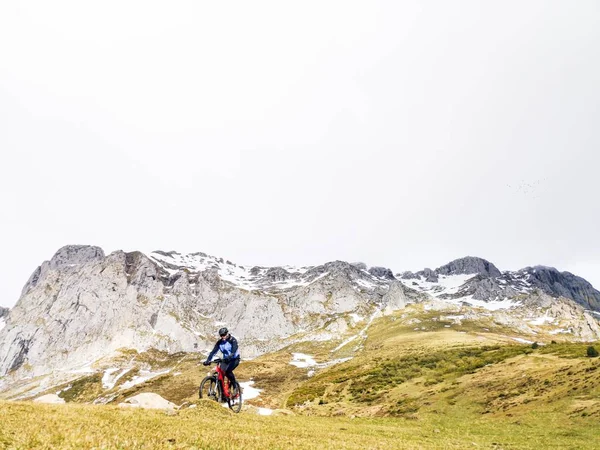Person auf dem Fahrrad auf den Hügeln mit gelbem und grünem Gras — Stockfoto