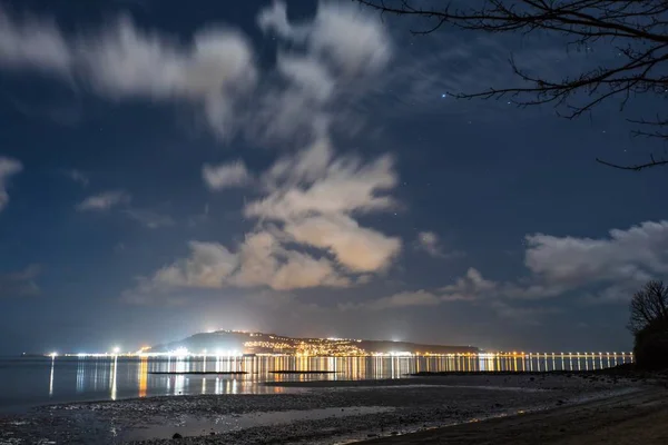 Shot of the city lights and night sky from the Sandsfoot beach in Dorset, Egyesült Királyság — Stock Fotó