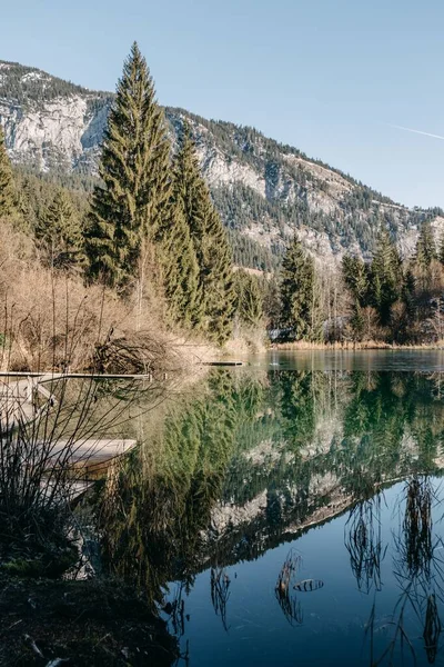 Vertikální obraz jezera obklopeného skalami a lesy se stromy odrážejícími se na vodě — Stock fotografie