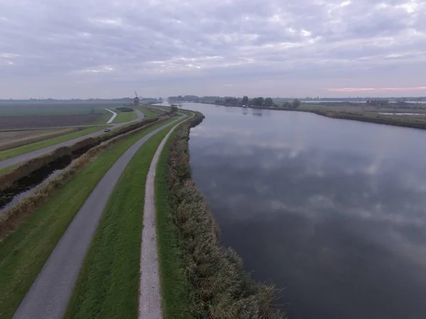 Dron widok holenderskiego krajobrazu pod zachmurzonym niebem z chmurami odbija się na wodzie w ciągu dnia — Zdjęcie stockowe