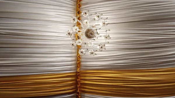 Tavanda beyaz ve sarı tekstil olan bir avizenin alçak açılı görüntüsü. — Stok fotoğraf