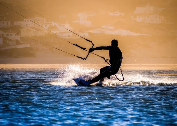 Silueta kitesurfer na moři pod slunečním světlem během západu slunce — Stock fotografie