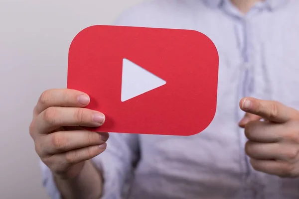 Широкоугольный снимок красного знака Youtube, который держит человек — стоковое фото
