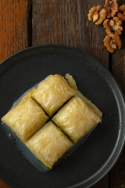 Vertikal Bild Baklava Skuren Kuber Tallrik Och Valnötter Ett Träbord — Stockfoto