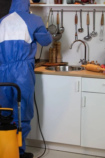 Tiro vertical de um engenheiro em traje azul e uma máscara anti-gás trabalhando na cozinha — Fotografia de Stock