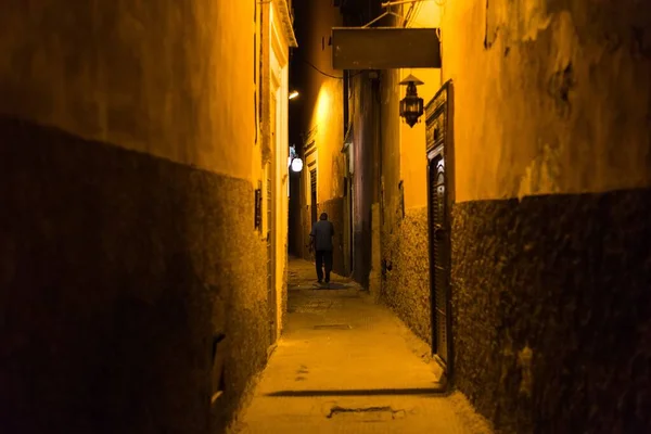 Person caminando por un camino en medio de edificios por la noche. — Foto de Stock