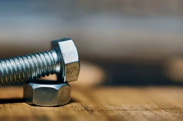 Nahaufnahme einer kleinen Schraube auf einer Holzoberfläche mit unscharfem Hintergrund — Stockfoto