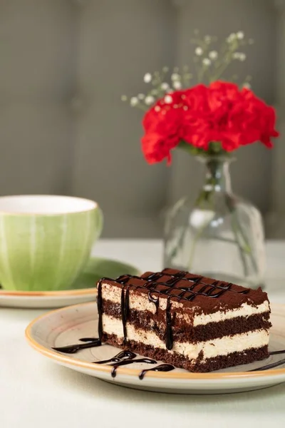 在一杯咖啡和玫瑰旁边的一块巧克力蛋糕的特写镜头 — 图库照片