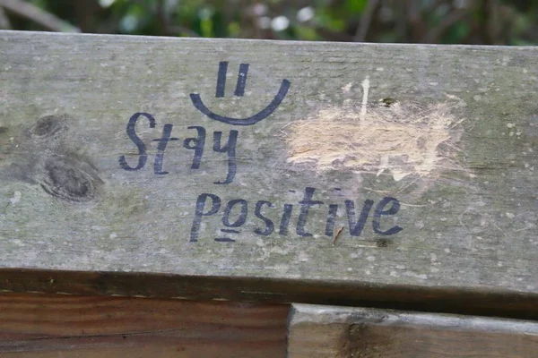 Szekrénykép fáról, a "Maradj pozitív" felirattal, homályos háttérrel — Stock Fotó