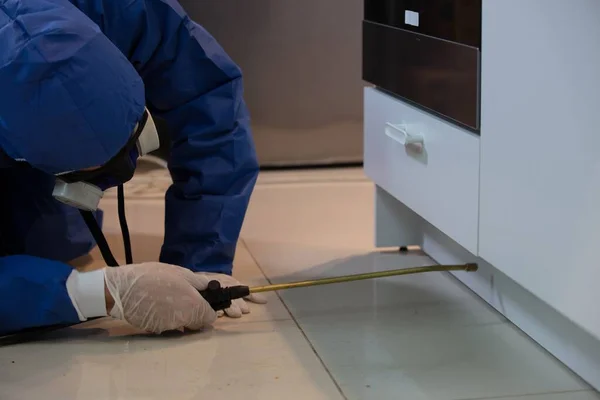 Stunning shot of a professional pest exterminator spraying a chemical under a kitchen counter — Stock Photo, Image